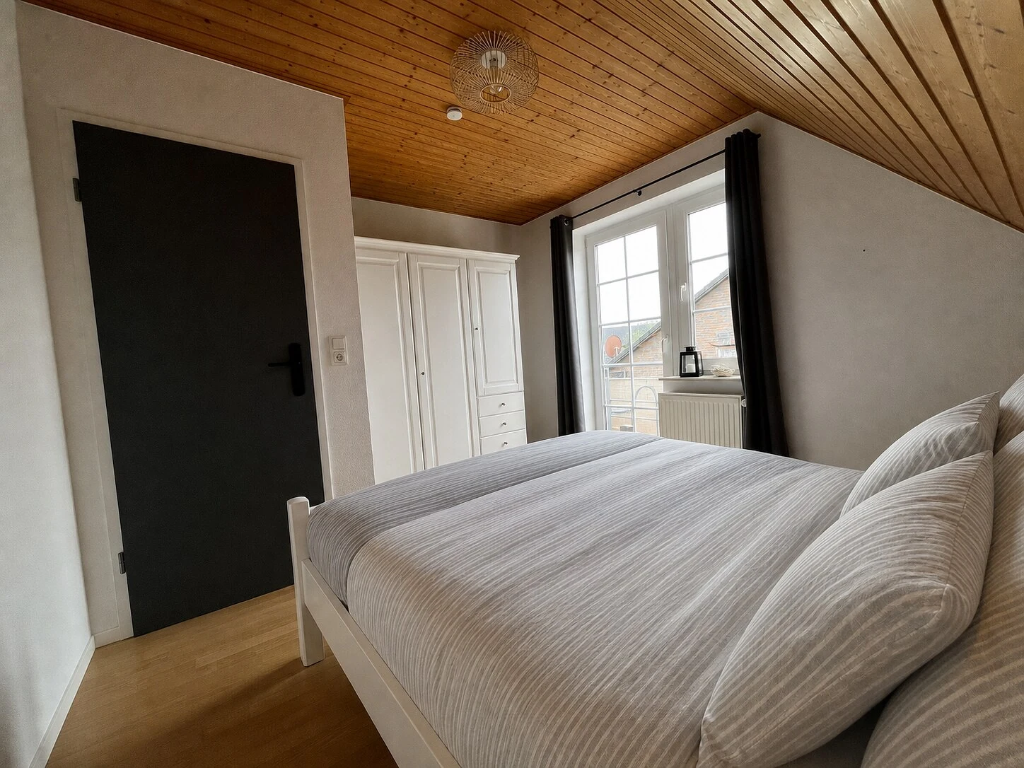 Schlafzimmer mit bezogenem Kingsize-Bett in ruhigen Grau- und Weißtönen