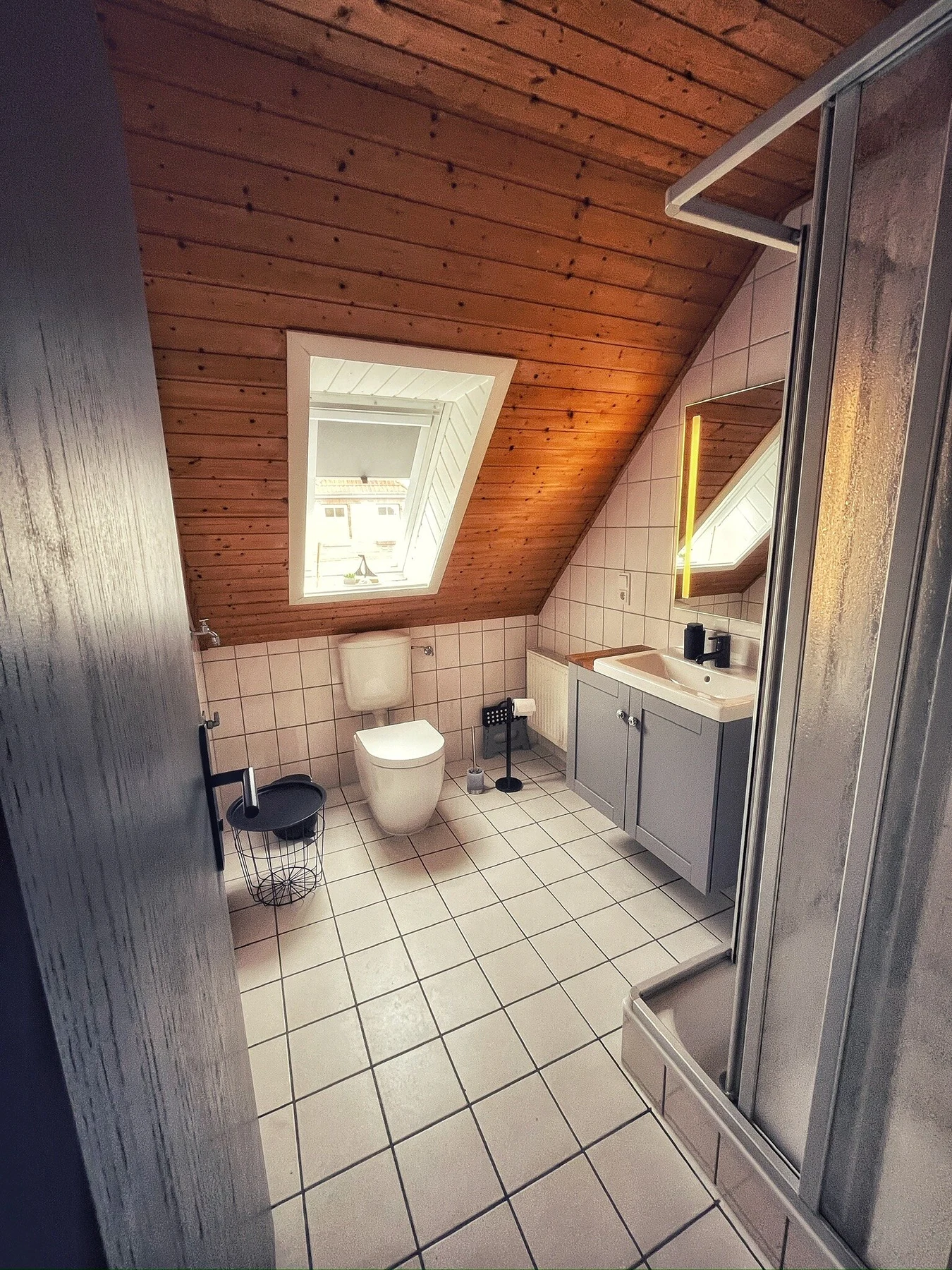 Badezimmer mit Dusche, Waschtisch, weißer Dachfensterlaibung und Plissee